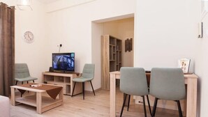 A modern living room with a television, two armchairs, a coffee table, and a bookshelf. - Trendy 2 Bd Apt in Galatsi (Athens)