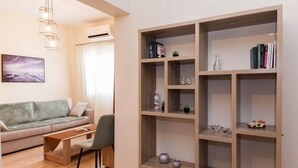 A living room with a sofa, a coffee table, a bookshelf, and a pendant light. - Trendy 2 Bd Apt in Galatsi (Athens)