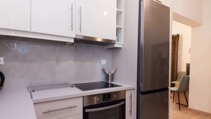 A modern kitchen with white cabinets, a stainless steel refrigerator, a built-in oven, and a sink with a kettle. - Trendy 2 Bd Apt in Galatsi (Athens)