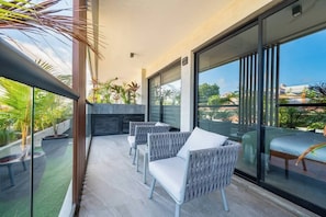 A balcony with wicker chairs, a glass door, and a view of the city.
