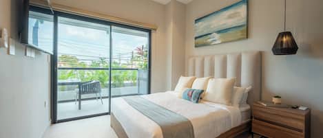 Une chambre avec un grand lit, une table de chevet, un tableau et une vue sur l’extérieur, accessible par une porte coulissante qui donne sur un espace extérieur.