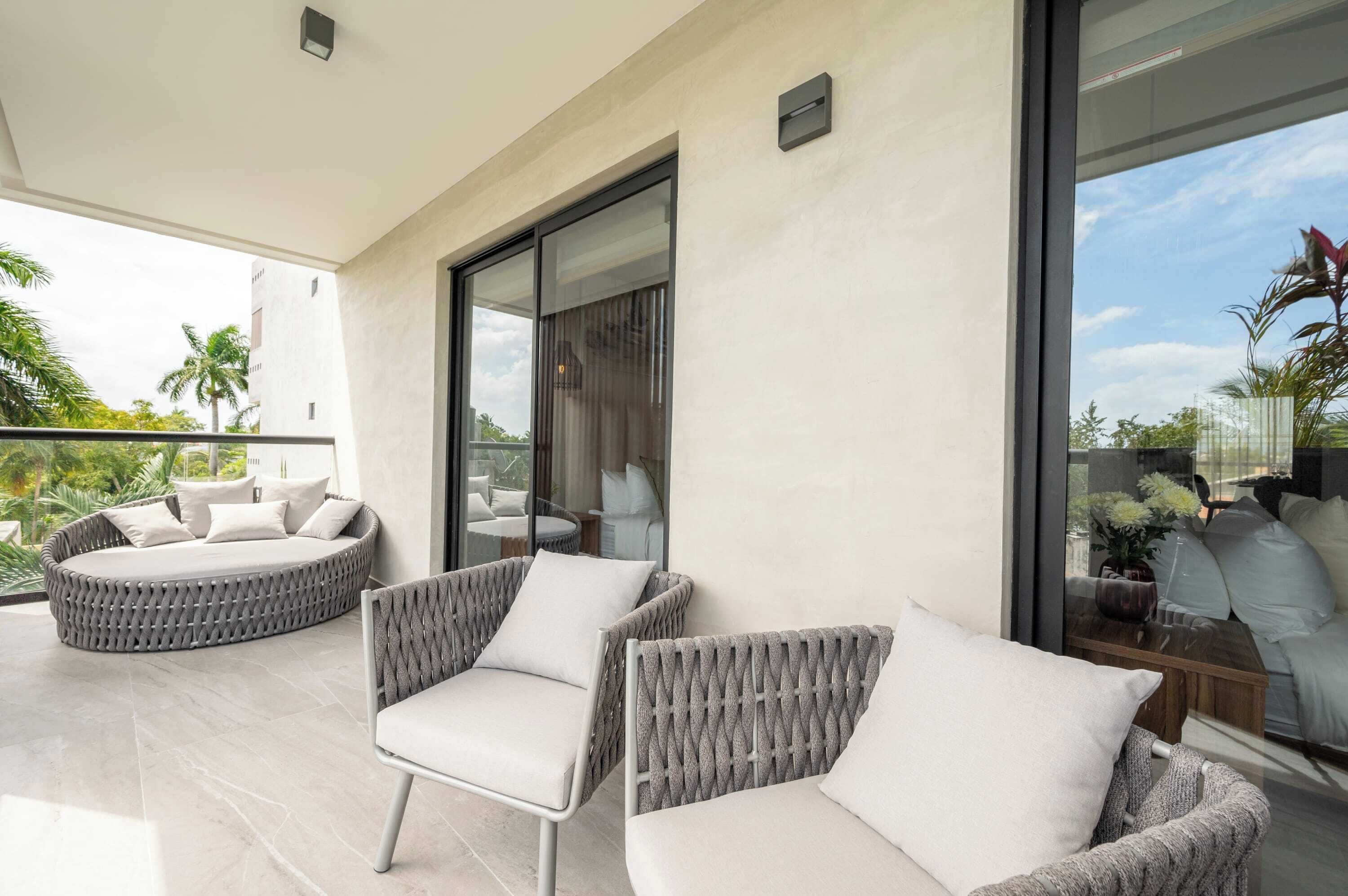 A balcony with wicker furniture, a glass door, and a view of the outdoors.
