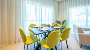 A dining area with a table set for four, yellow chairs, and a white sofa.