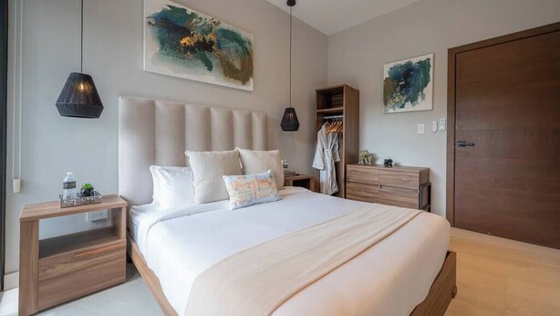 A modern bedroom with a large bed, bedside tables, a wardrobe, and abstract artwork on the walls.