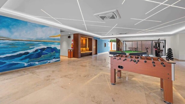 A modern indoor space with a foosball table, a pool table, and a large mural of the ocean. - Kippal Holbox 2 Bedroom 2 Baths and a Private Balcony (San Miguel de Cozumel)