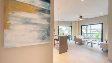 A modern living room with a dining area, large windows, and a ceiling fan.