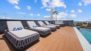 A rooftop pool area with lounge chairs and a view of the city.