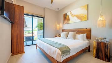 A modern bedroom with a large bed, a TV, a ceiling fan, and a view of the outdoors.