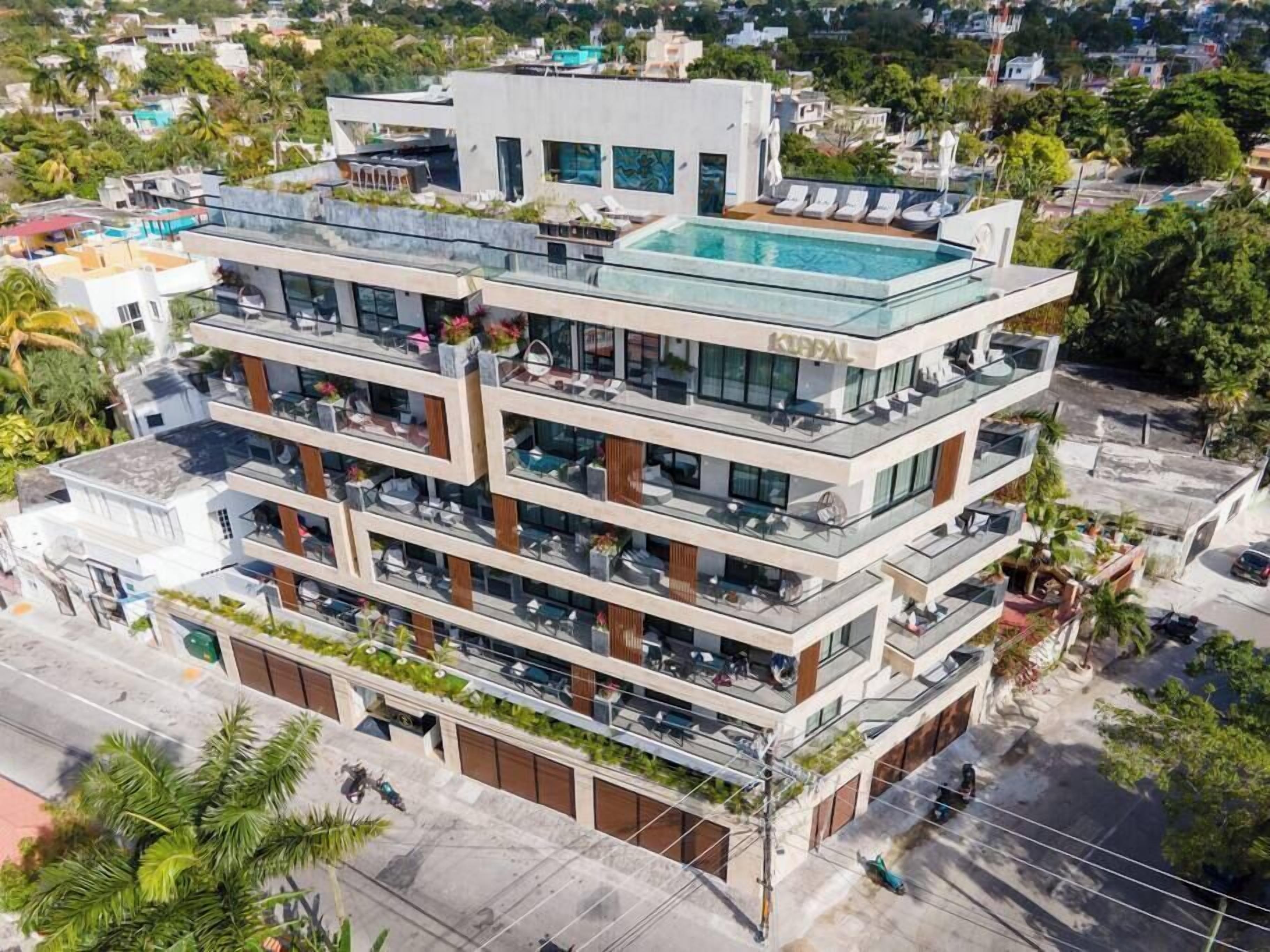 A multi-story hotel with a rooftop pool, balconies, and a modern architectural design.