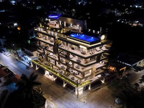A multi-story hotel with a rooftop pool, multiple balconies, and outdoor lighting. - Kippal Apartamento con vista al mar (San Miguel de Cozumel)
