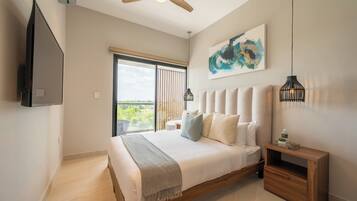 A modern bedroom with a large bed, a ceiling fan, a mounted TV, and a view of the outdoors.