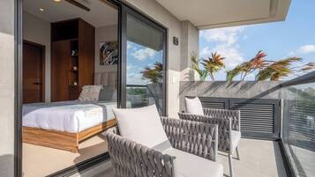 A balcony with a bed, wicker furniture, and potted plants.