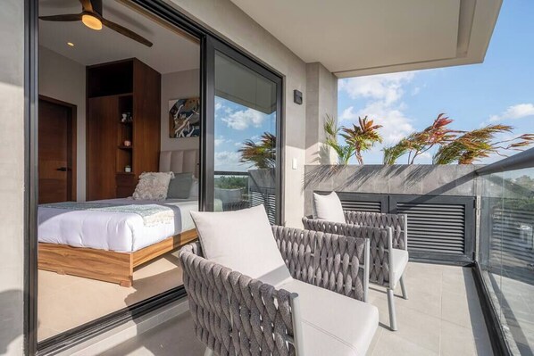 Un balcón con cama, muebles de mimbre y plantas en macetas.