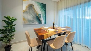 A dining area with a wooden table, four chairs, a potted plant, and a painting on the wall. - Kippal Tulum  2 Bedroom 2 Baths  Ocean View Balcony (San Miguel de Cozumel)