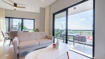 En moderne stue med sofa, sofabord og en balkon med udsigt.