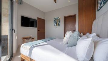 A bedroom with a bed, a TV, a ceiling fan, and a door.