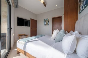 Un dormitorio con cama, televisión, ventilador de techo y puerta.