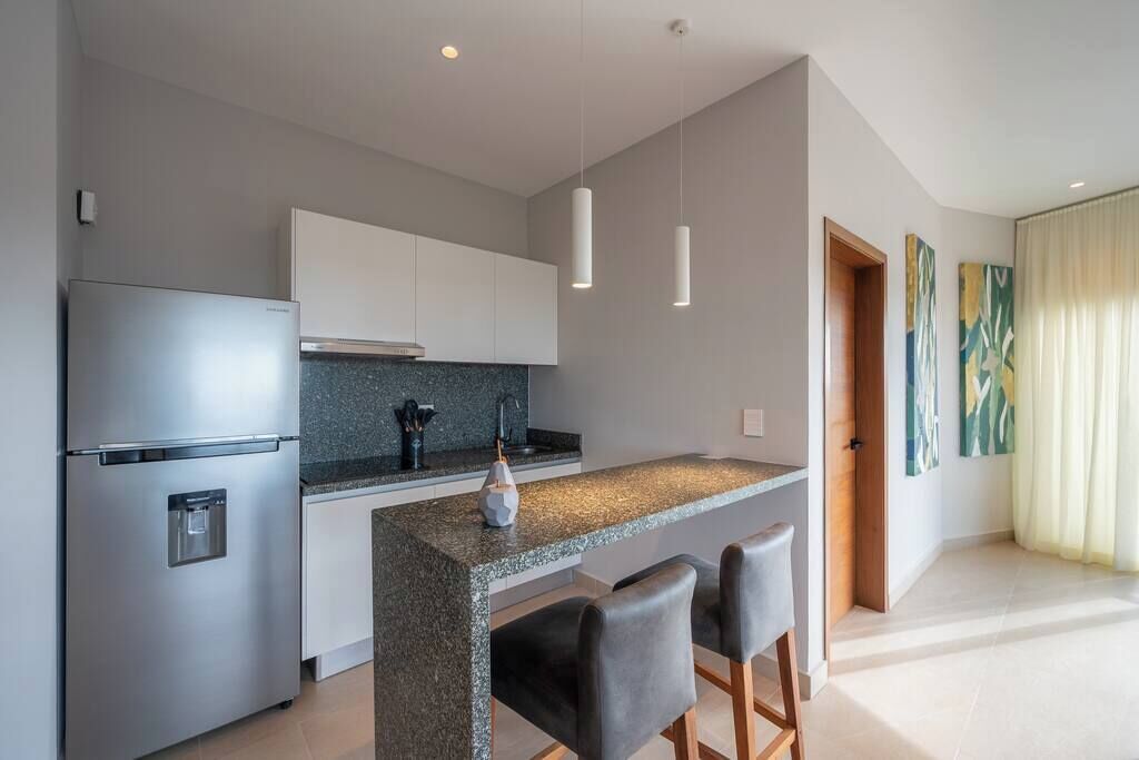 A modern kitchen with a granite countertop, stainless steel appliances, and pendant lighting.