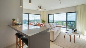 Un espacio habitable moderno con isla de cocina, zona de comedor y asientos con vista a la ciudad.