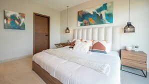 Un dormitorio moderno con una cama grande, una mesita de noche de madera y arte abstracto en las paredes.