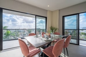 A dining area with a table set for four, large windows, and a view of the cityscape.