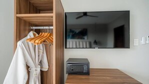 Una habitación con un armario de madera, un televisor de pantalla plana y un pequeño dispositivo negro sobre una mesa de madera.