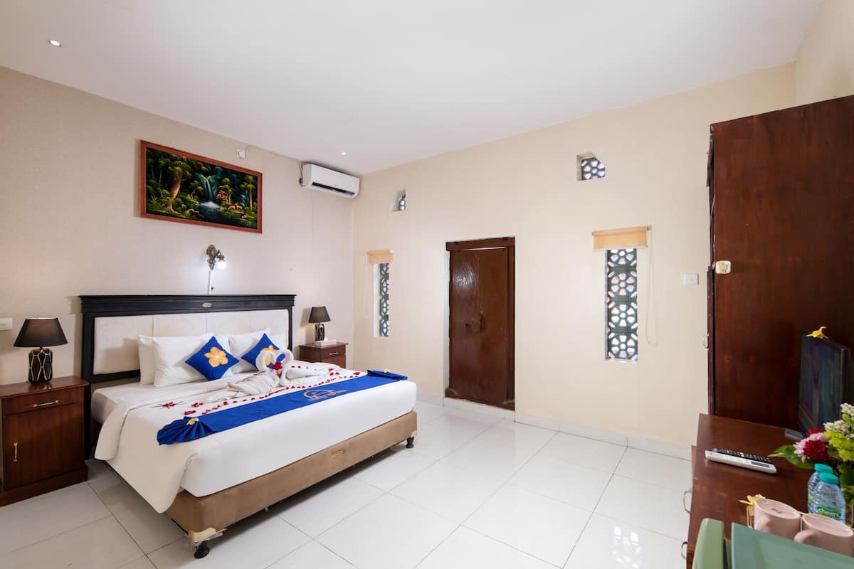 A hotel room with a bed, nightstands, a desk, and a door.