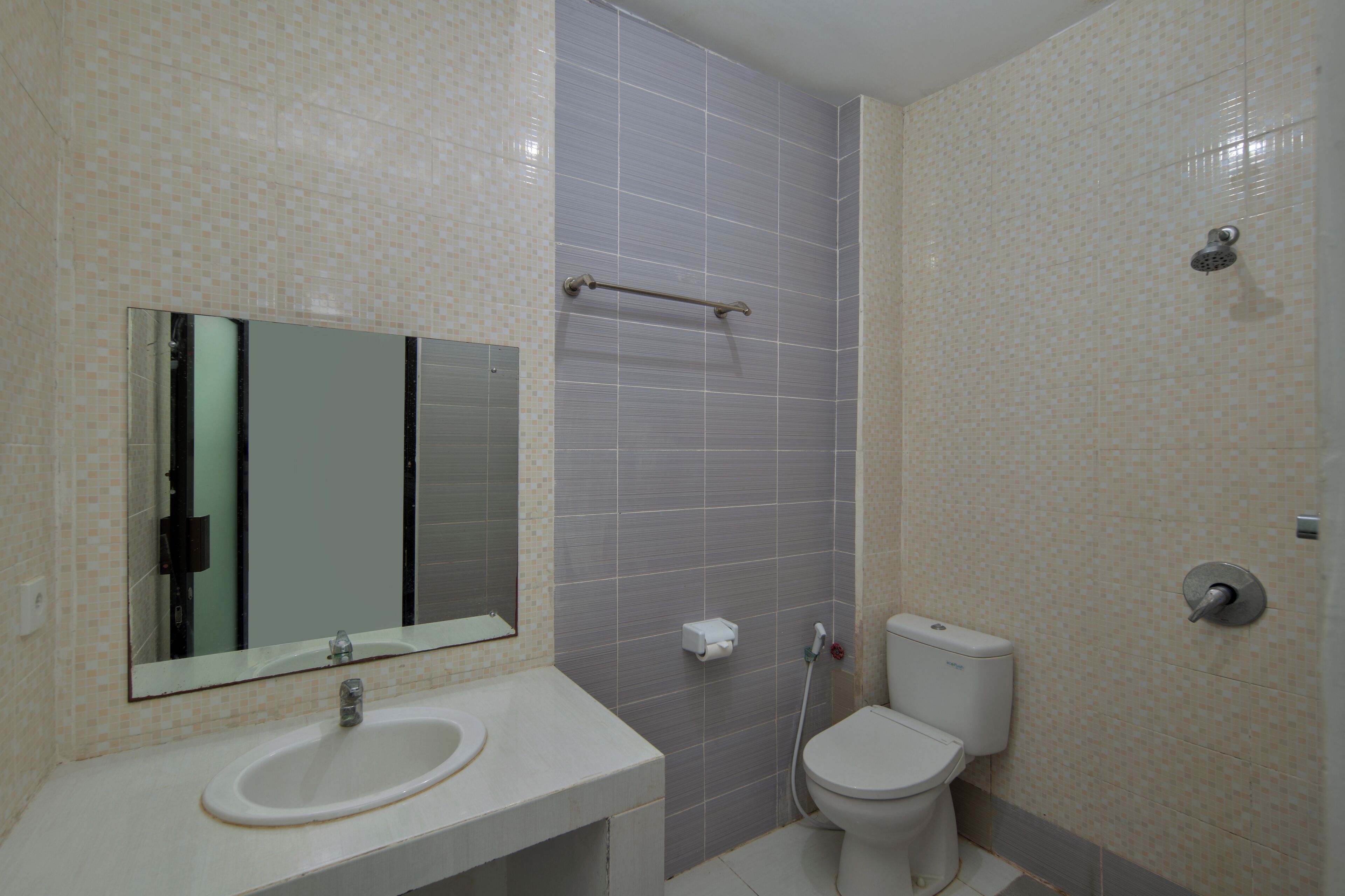 A bathroom with a sink, mirror, toilet, and a shower area.
