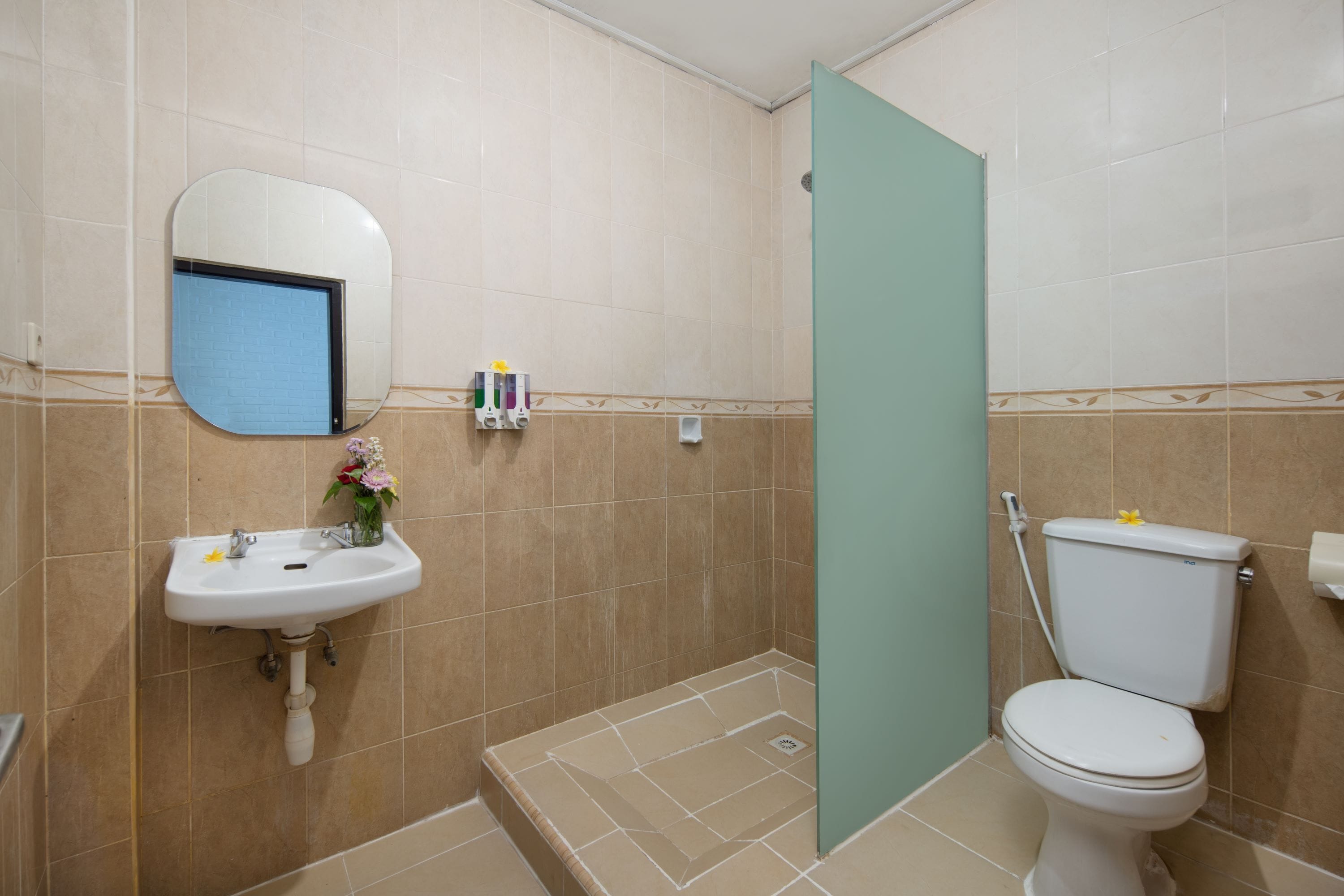 A bathroom with a sink, mirror, toilet, and shower area.
