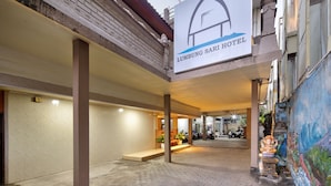 A hotel entrance with a sign reading "Lumbung Sari Hotel," a covered outdoor area with columns, and a paved walkway. - Hotel Lumbung Sari Legian (Legian)