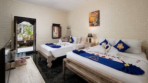 A hotel room with two beds, a desk, a TV, and a window with a view of greenery. - Hotel Lumbung Sari Legian (Legian)
