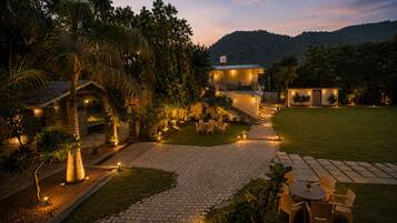 A well-lit outdoor area with a paved walkway, seating arrangements, and a building with multiple windows.