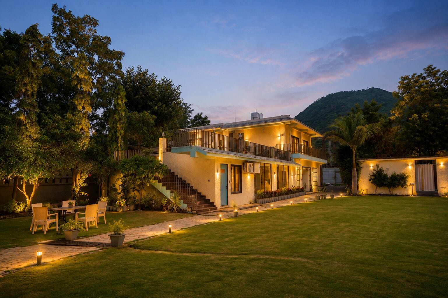 A two-story house with a balcony, a staircase, and a well-maintained lawn.