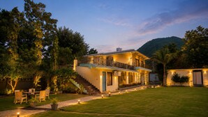 A two-story house with a balcony, a staircase, and a well-maintained lawn. - Banjara Hills Resort (Udaipur)