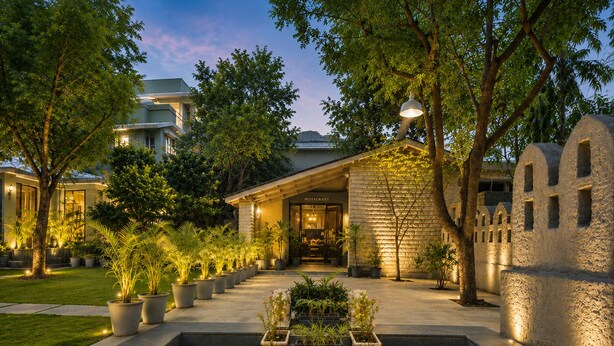 Un espacio exterior bien iluminado con un sendero de piedra que conduce a un edificio que dice 'RESTAURANT'.