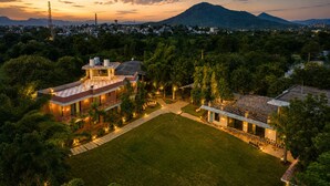 Un barrio residencial con una casa grande que tiene un amplio césped, piscina y una montaña al fondo.