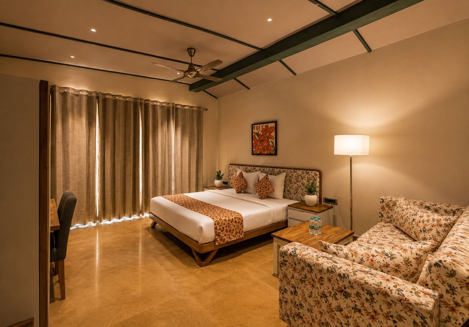 A hotel room with a bed, a sofa, a desk, and a lamp.