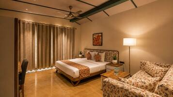 A hotel room with a bed, a sofa, a desk, and a lamp.
