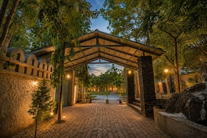 An arched entrance with stone walls and a brick pathway leading to a building. - Banjara Hills Resort (Udaipur)