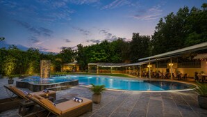 Una piscina con hidromasaje, sillas de descanso y una zona de estar techada al aire libre.