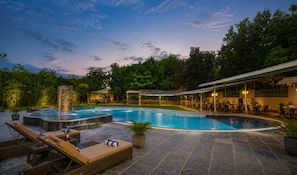 A swimming pool with a hot tub, lounge chairs, and a covered outdoor seating area. - Banjara Hills Resort (Udaipur)