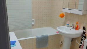 A bathroom with a bathtub, sink, toilet, and a mirror above the sink. - Studio Quiberon Face Mer vue sur les Îles (Quiberon)