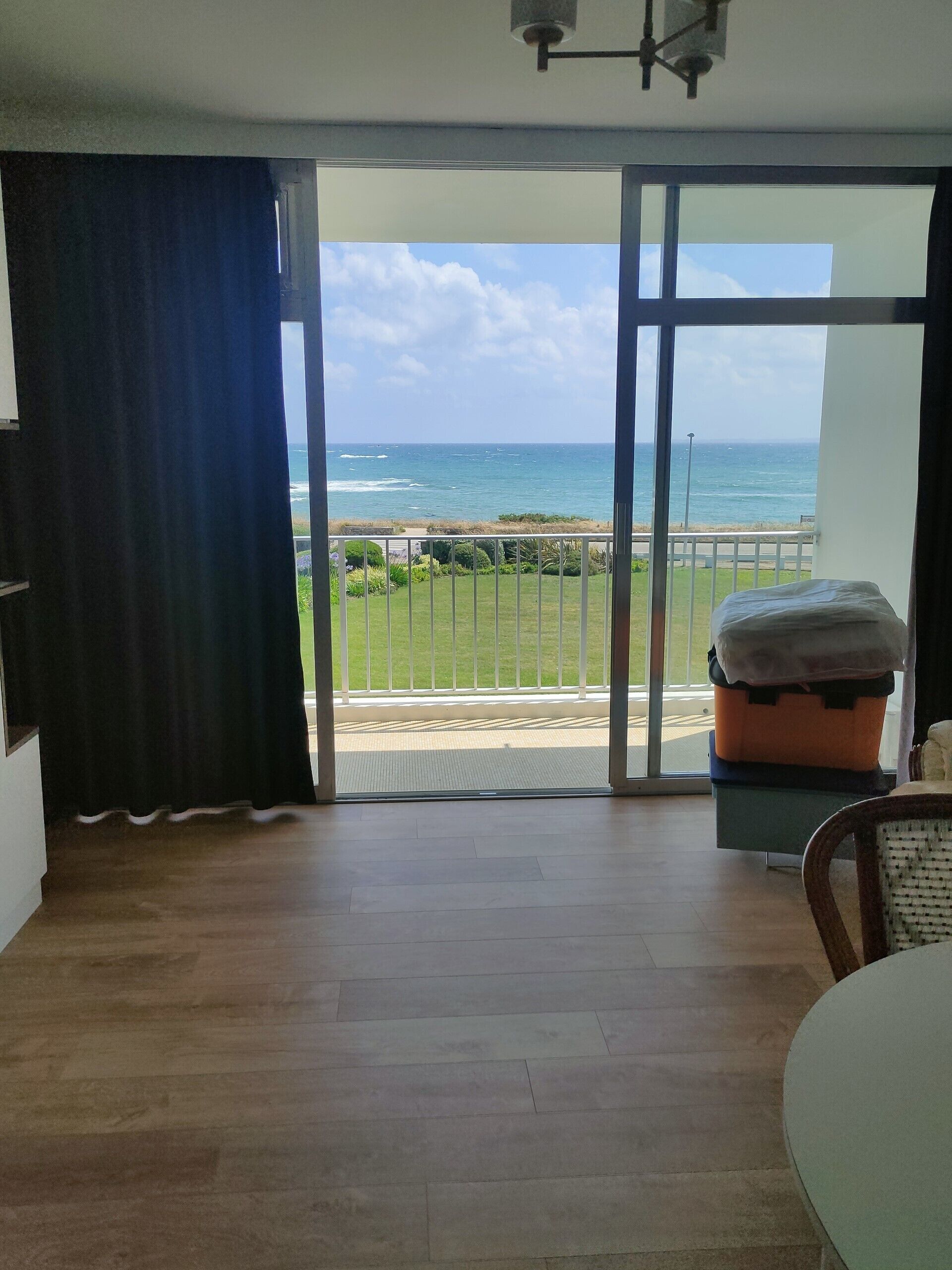A room with a view of the ocean, a sliding glass door, a bed, and a table.