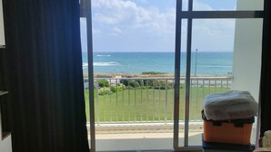 A room with a view of the ocean, a sliding glass door, a bed, and a table. - Studio Quiberon Face Mer vue sur les Îles (Quiberon)