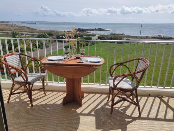 Un balcón con una mesa lista para dos personas, con vistas a la costa.