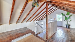 An attic room with wooden beams, a staircase, and a hanging light fixture. - Private Gem in Heart of Downtown Newport  (Newport)