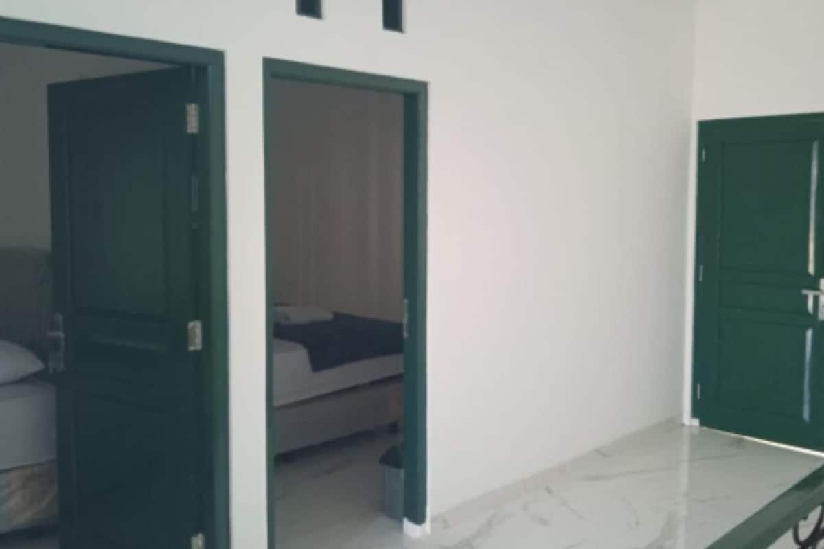 Quarto de hotel com cama, mesa de cabeceira e porta verde.