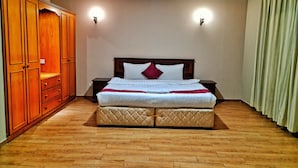 Une chambre d’hôtel avec un grand lit, une armoire en bois et deux lampes fixées au mur.
