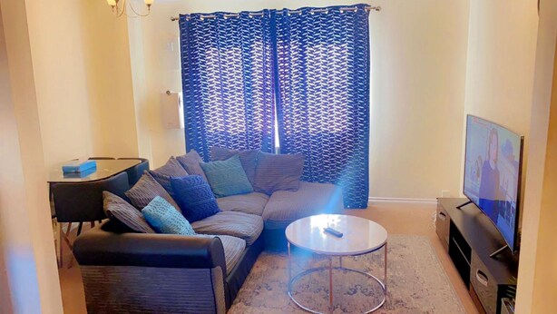 A living room with a sofa, coffee table, TV, and patterned curtains.