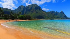 A beach with clear turquoise water, palm trees, and a mountain in the background. - Garden View Suite  Pono Kai Resort PK-K303 (Kapaʻa)